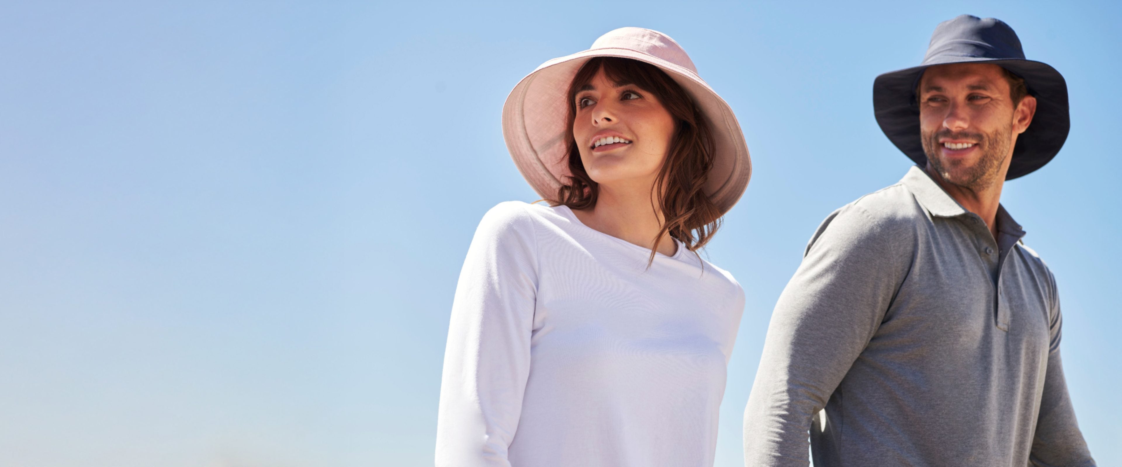 A woman and a man in Solbari sun hats with a blue sky in the background.