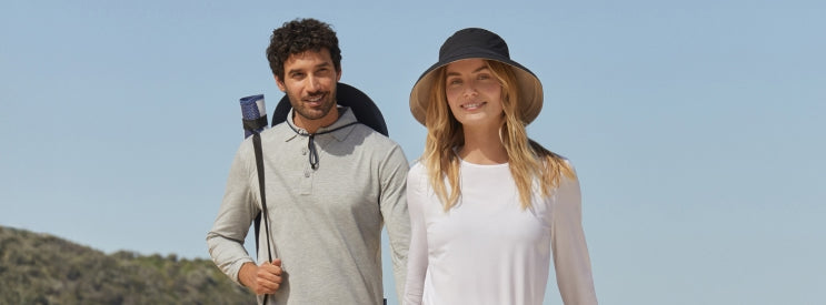 Two people with hiking equipment standing against a clear blue sky.