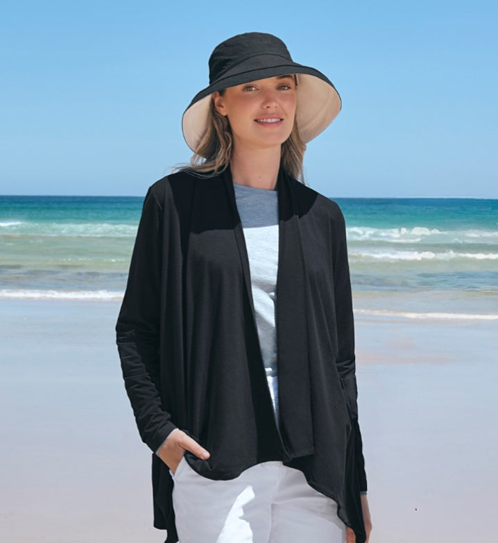 Woman wearing a Solbari UPF 50+ black sun hat and black cardigan on a beach